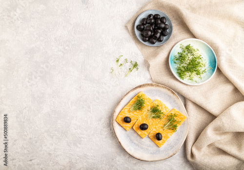 Marble cheese with olives and watercress microgreen on gray concrete. top view, copy space.