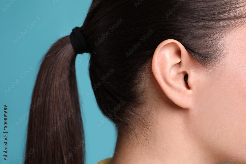 Woman on light blue background, closeup of ear Woman on light blue background, closeup of ear