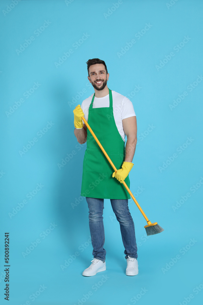Man with yellow broom on light blue background Man with yellow broom on light blue background