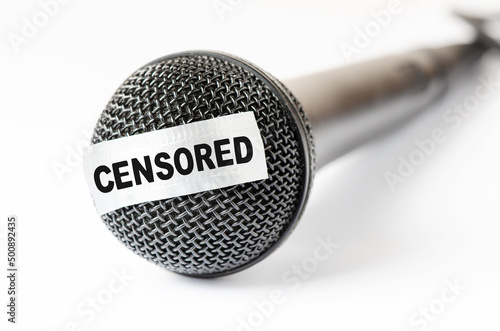 The microphone is sealed with sticky tape. The concept of restricting freedom of speech or obscene language. Closeup, white background. photo