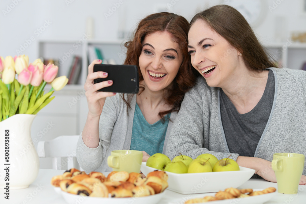 Portrait of two female friends looking at smartphone