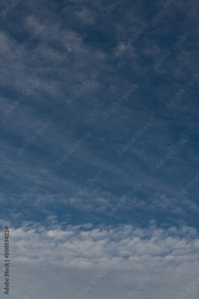 Obraz premium vertical backdrop of blue sky with wispy clouds on top of puffy clouds at bottom nice day looking up climate change weather or environmental vertical format backdrop background or wallpaper 