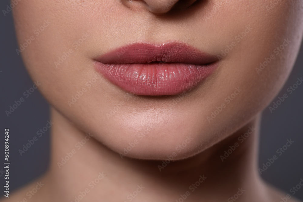 Woman with beautiful lips on grey background, closeup
