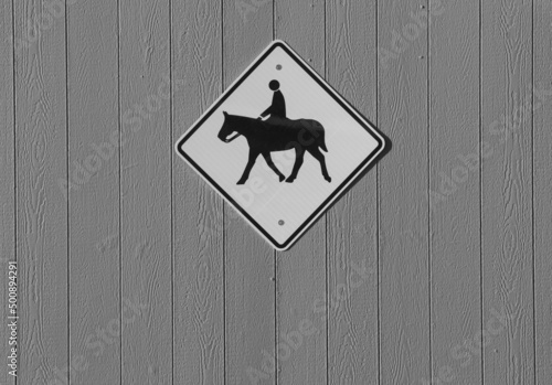 diamond shaped horse crossing or horse rider sign in blacl and white signifying riding horses in the area or horse crossing road diamond shaped sign with silhouette of horse and rider horizontal  photo