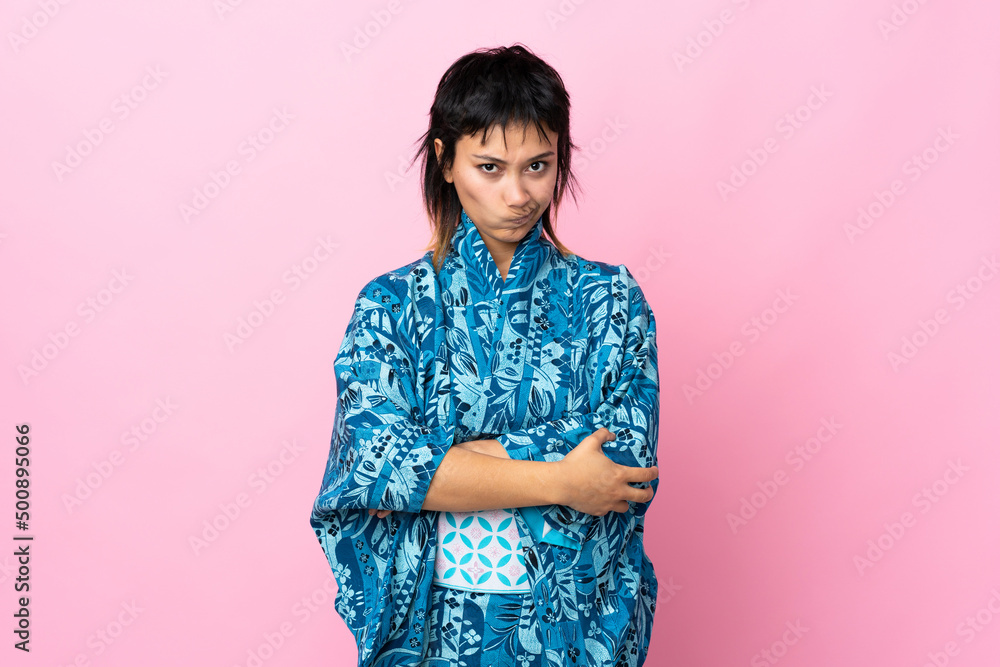 Young woman wearing kimono over isolated blue background feeling upset Young woman wearing kimono over isolated blue background feeling upset