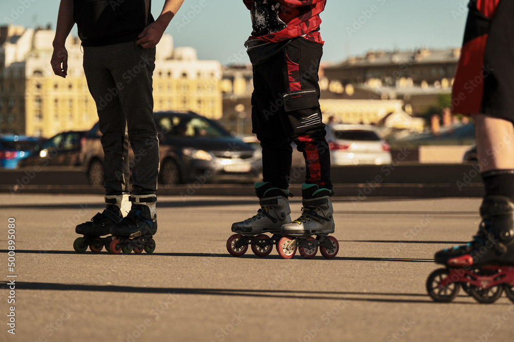 Obraz premium Three men stand on roller skates in the city next to the road.