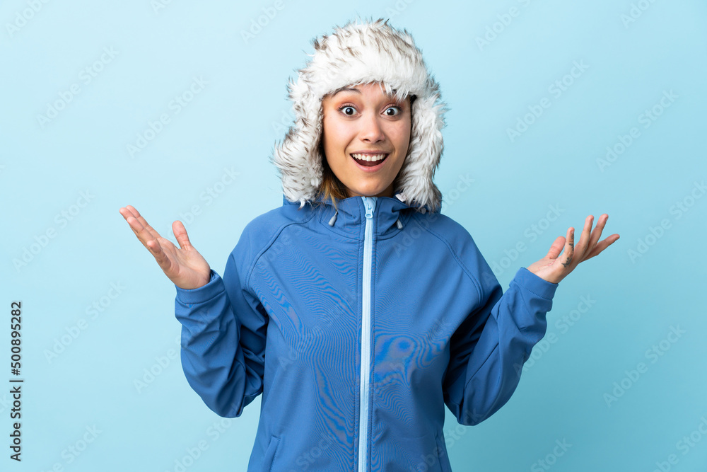 Young Uruguayan girl with winter hat isolated on blue background with surprise facial expression Young Uruguayan girl with winter hat isolated on blue background with surprise facial expression