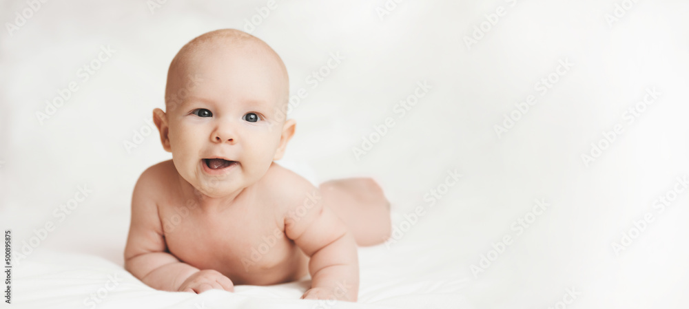 Cute small boy lying at bed. Childhood concept. Light background. Smiling child. Happy emotion. Copyspace. Mockup. Horizontal banner. White clothes Cute small boy lying at bed. Childhood concept. Light background. Smiling child. Happy emotion. Copyspace. Mockup. Horizontal banner. White clothes