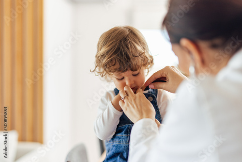 A female pediatrician on a home visit,examines a toddler. photo