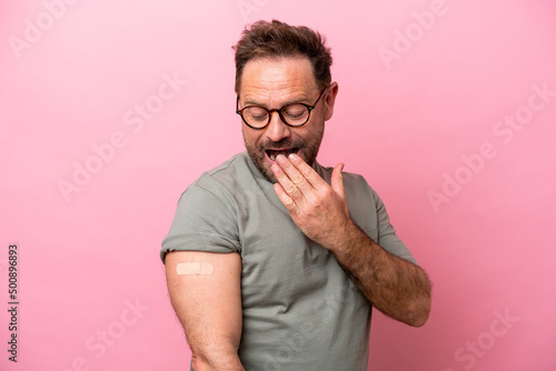 Middle age man wearing a band aids isolated on pink background with surprise and shocked facial expression photo