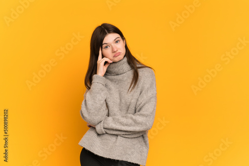 Young Ukrainian girl isolated on yellow background thinking an idea © luismolinero