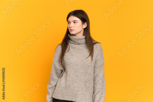 Young Ukrainian girl isolated on yellow background looking to the side © luismolinero