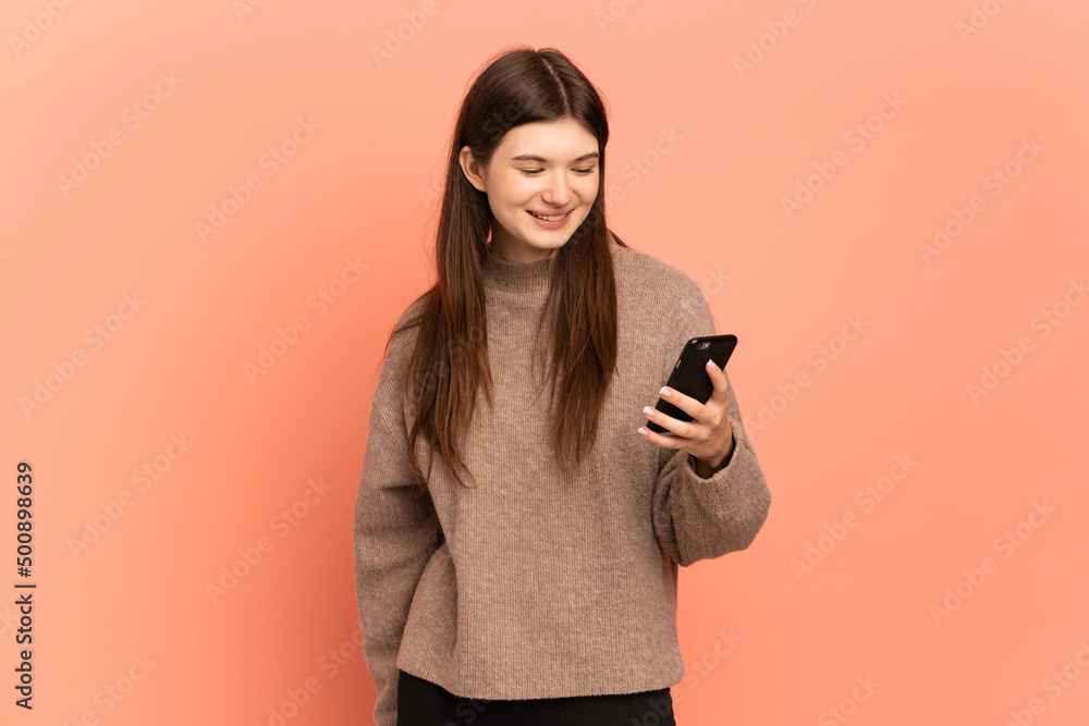Young Ukrainian girl isolated on pink background sending a message or email with the mobile Young Ukrainian girl isolated on pink background sending a message or email with the mobile