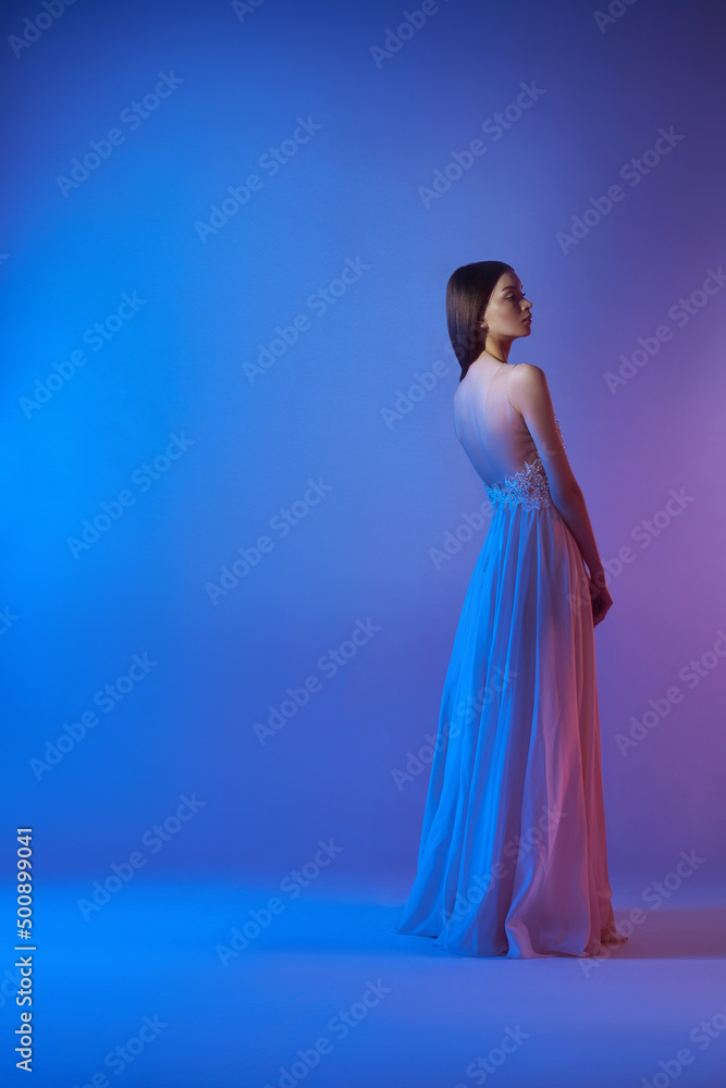 Fototapeta premium Art fashion beautiful elegant woman in blowing flying dress. Freedom concept in neon color light. Fashion style of flowing dress on body woman