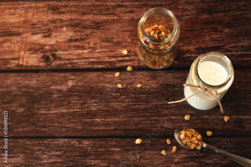 fermented milk product kefir in a glass jar with granola on a beige background