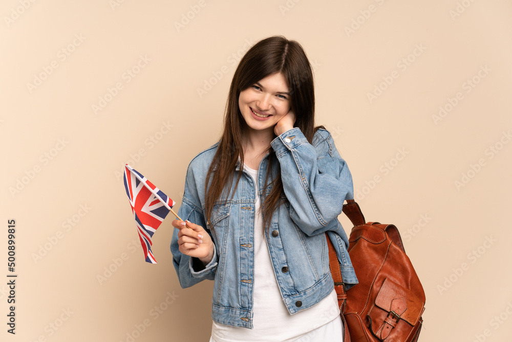Young Ukrainian girl holding an United Kingdom flag isolated on beige background laughing Young Ukrainian girl holding an United Kingdom flag isolated on beige background laughing