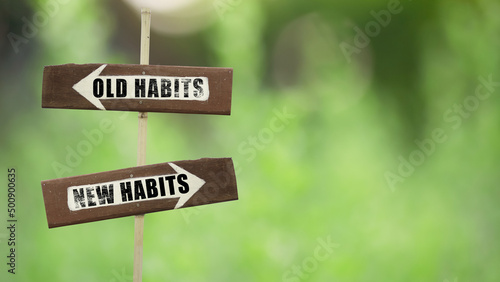 Old habits- New habits on a wooden signpost on a natural green background.copy space. photo