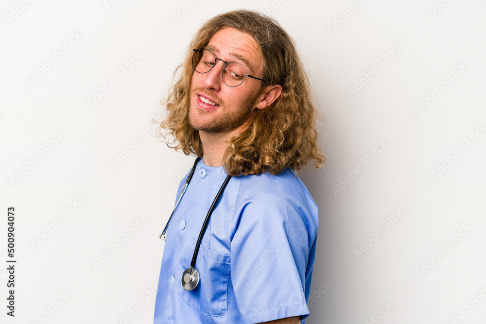 Young nurse caucasian man isolated on blue background looks aside smiling, cheerful and pleasant. Young nurse caucasian man isolated on blue background looks aside smiling, cheerful and pleasant.