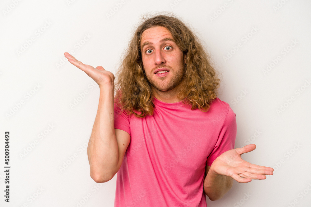 Young caucasian man isolated on white background confused and doubtful shrugging shoulders to hold a copy space.