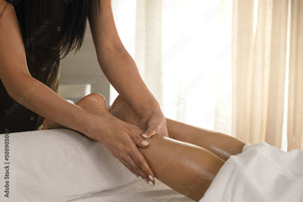Fototapeta premium Professional female physiotherapist with doing legs massage for relaxed woman