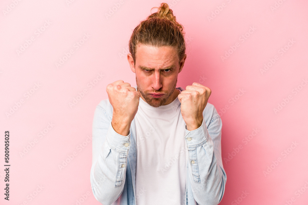 Young caucasian man isolated on pink background showing fist to camera, aggressive facial expression. Young caucasian man isolated on pink background showing fist to camera, aggressive facial expression.