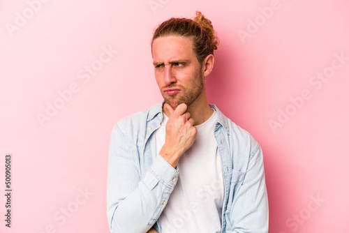 Young caucasian man isolated on pink background suffers pain in throat due a virus or infection.