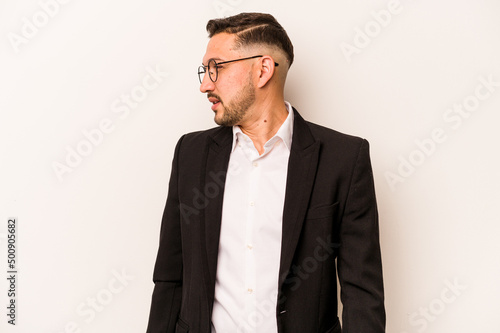 Business hispanic man isolated on white background looks aside smiling, cheerful and pleasant.