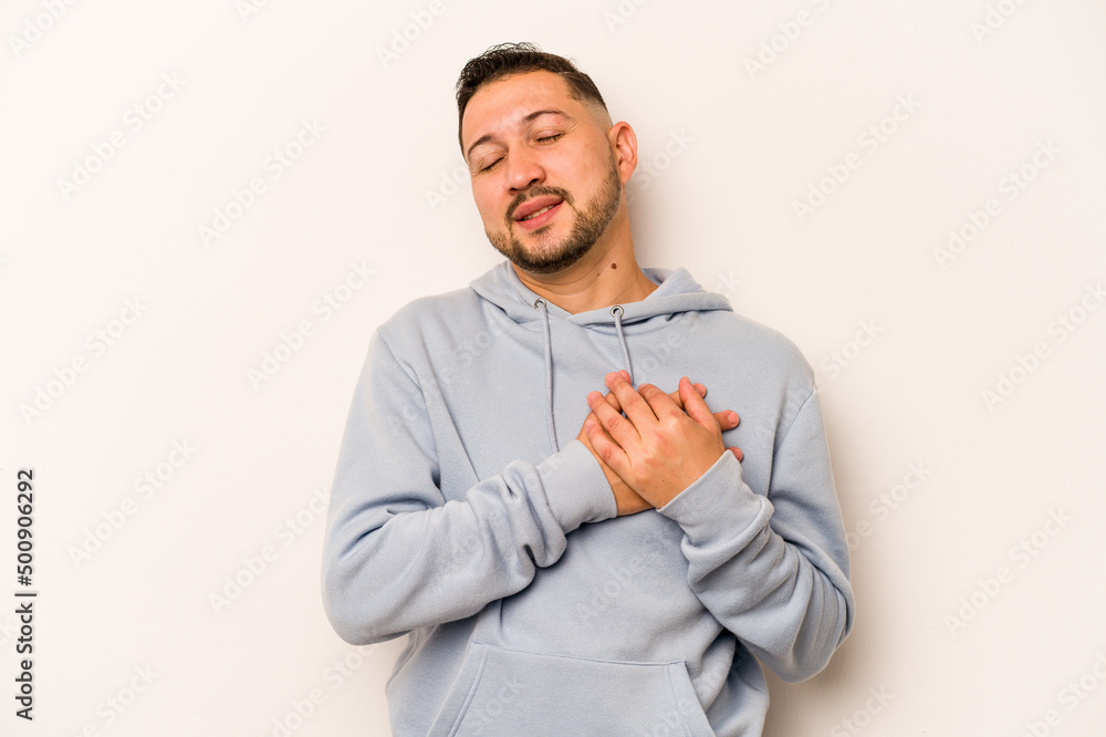 Young hispanic man isolated on white background has friendly expression, pressing palm to chest. Love concept. Young hispanic man isolated on white background has friendly expression, pressing palm to chest. Love concept.