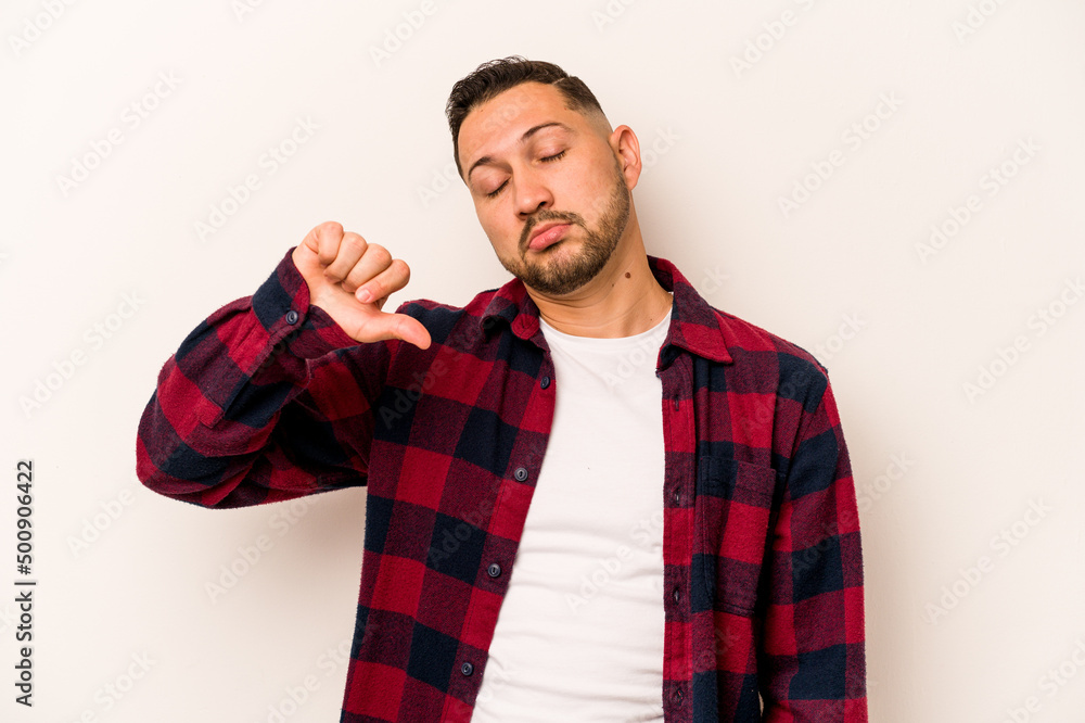Young hispanic man isolated on white background showing a dislike gesture, thumbs down. Disagreement concept. Young hispanic man isolated on white background showing a dislike gesture, thumbs down. Disagreement concept.