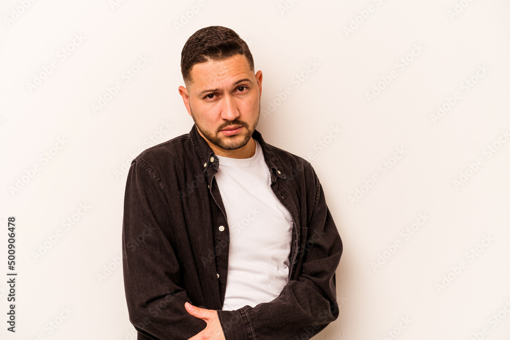 Fototapeta premium Young hispanic man isolated on white background suspicious, uncertain, examining you.