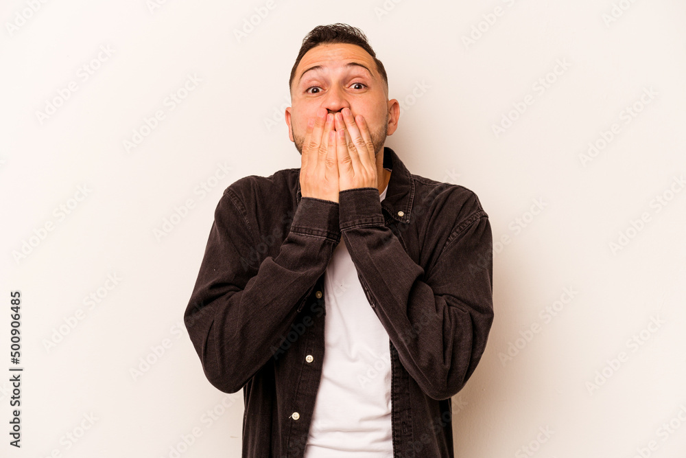 Young hispanic man isolated on white background shocked covering mouth with hands. Young hispanic man isolated on white background shocked covering mouth with hands.