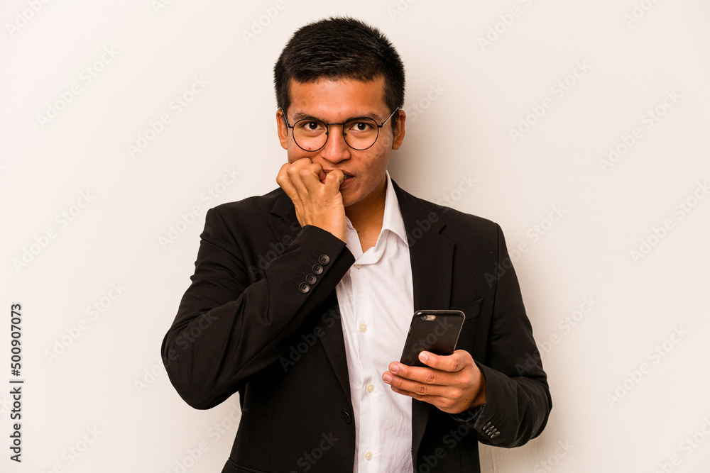 Young business hispanic man holding mobile phone isolated on white background biting fingernails, nervous and very anxious. Young business hispanic man holding mobile phone isolated on white background biting fingernails, nervous and very anxious.