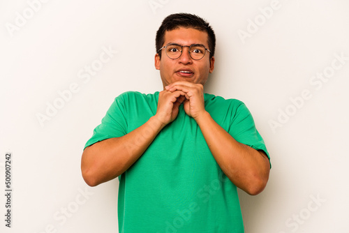 Young hispanic man isolated on white background praying for luck, amazed and opening mouth looking to front.