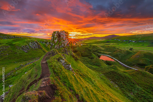 Landscape in Scotland on the Isle of Skye in the evening. Summer sunset with Castle Ewen rock. sun star on the horizon. path on the cliff edge. Road with a small lake photo