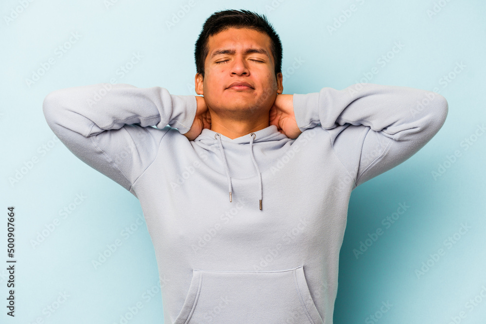 Young hispanic man isolated on blue background feeling confident, with hands behind the head. Young hispanic man isolated on blue background feeling confident, with hands behind the head.
