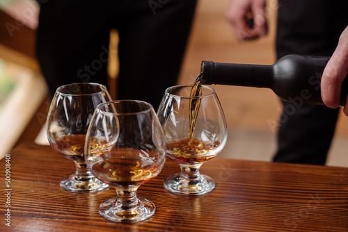 Groom with bestmen drinks whiskey from glasses. Closeup photo