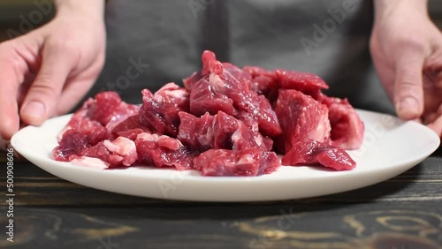 Person is putting raw sliced meat on a table