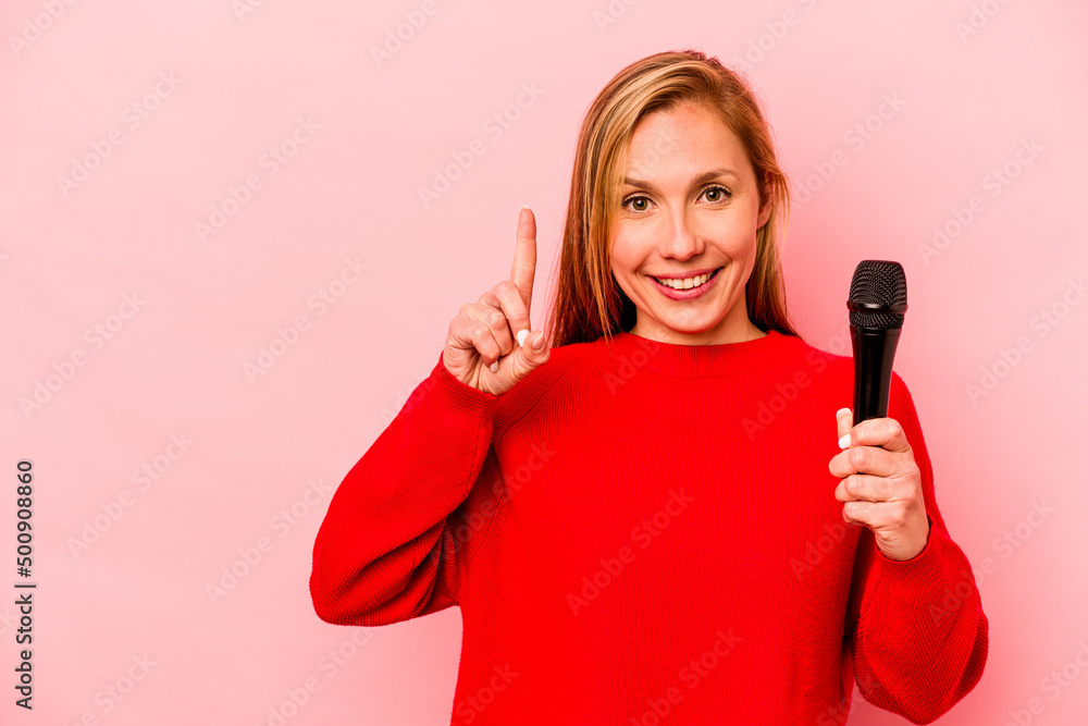 Young caucasian singer woman isolated on pink background showing number one with finger. Young caucasian singer woman isolated on pink background showing number one with finger.