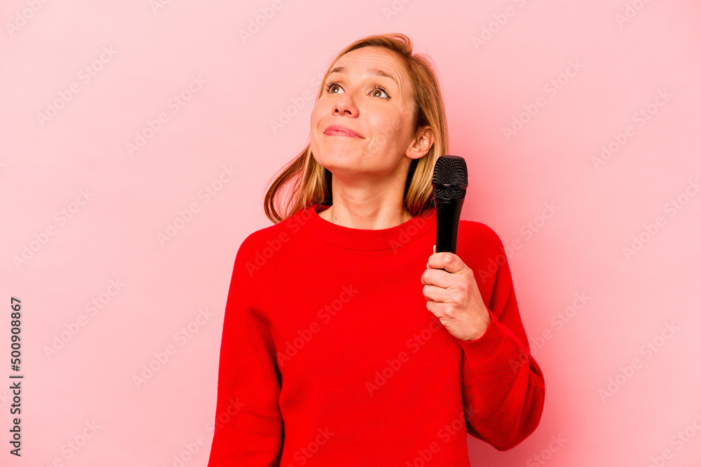 Young caucasian singer woman isolated on pink background dreaming of achieving goals and purposes Young caucasian singer woman isolated on pink background dreaming of achieving goals and purposes