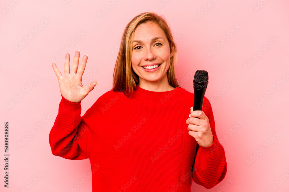 Young caucasian singer woman isolated on pink background smiling cheerful showing number five with fingers. Young caucasian singer woman isolated on pink background smiling cheerful showing number five with fingers.