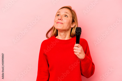 Young caucasian singer woman isolated on pink background dreaming of achieving goals and purposes