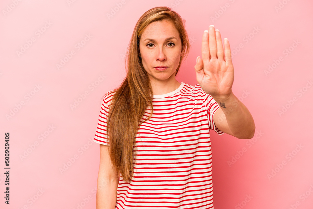 Young caucasian woman isolated on pink background standing with outstretched hand showing stop sign, preventing you. Young caucasian woman isolated on pink background standing with outstretched hand showing stop sign, preventing you.