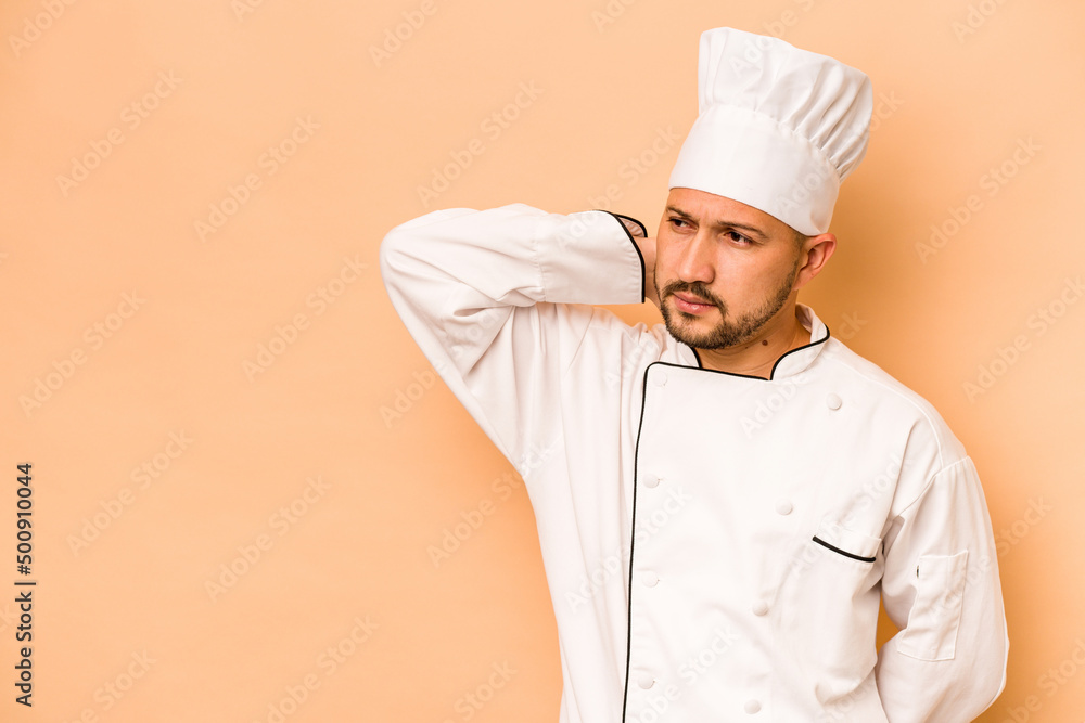 Hispanic chef man isolated on beige background touching back of head, thinking and making a choice. Hispanic chef man isolated on beige background touching back of head, thinking and making a choice.