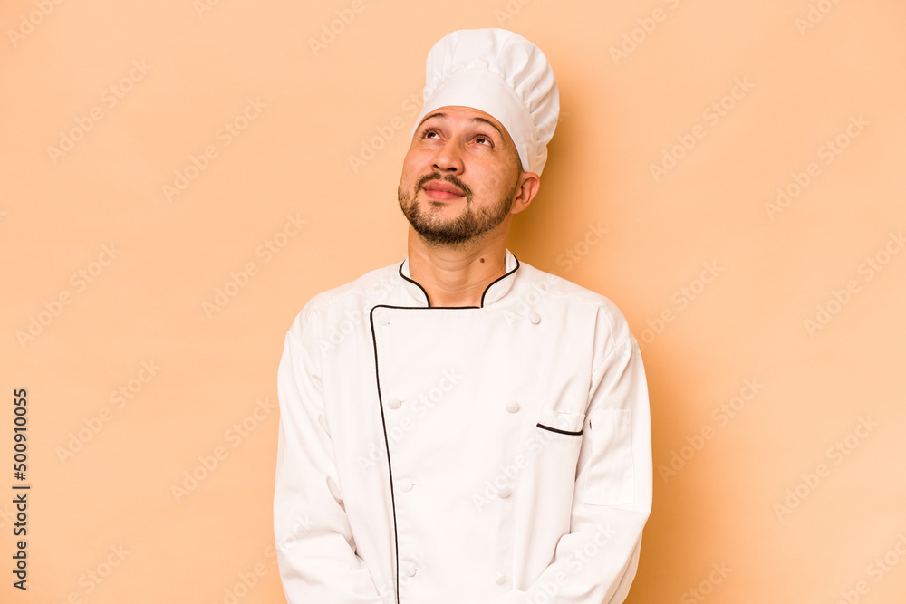 Hispanic chef man isolated on beige background dreaming of achieving goals and purposes Hispanic chef man isolated on beige background dreaming of achieving goals and purposes