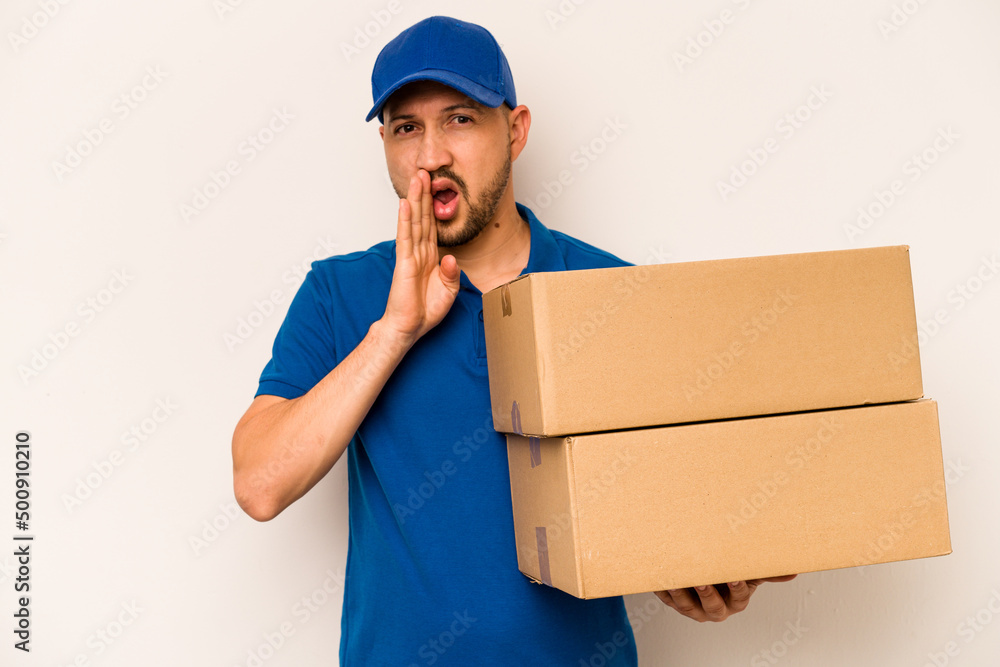 Hispanic delivery man isolated on white background is saying a secret hot braking news and looking aside Hispanic delivery man isolated on white background is saying a secret hot braking news and looking aside