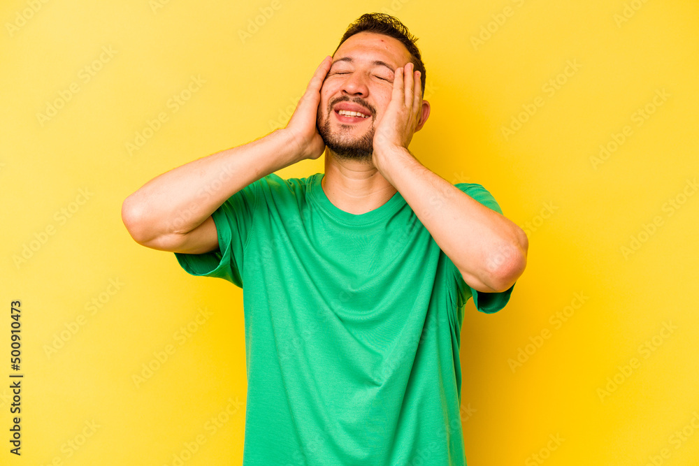 Young hispanic man isolated on yellow background laughs joyfully keeping hands on head. Happiness concept. Young hispanic man isolated on yellow background laughs joyfully keeping hands on head. Happiness concept.