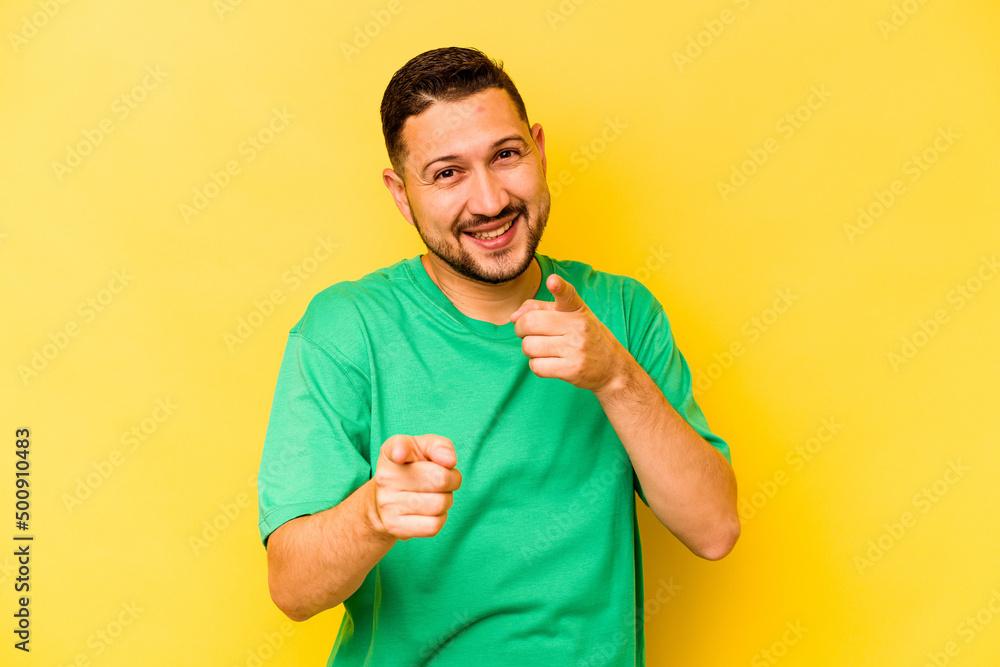 Young hispanic man isolated on yellow background pointing to front with fingers. Young hispanic man isolated on yellow background pointing to front with fingers.