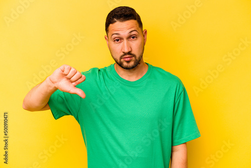 Young hispanic man isolated on yellow background showing a dislike gesture, thumbs down. Disagreement concept.