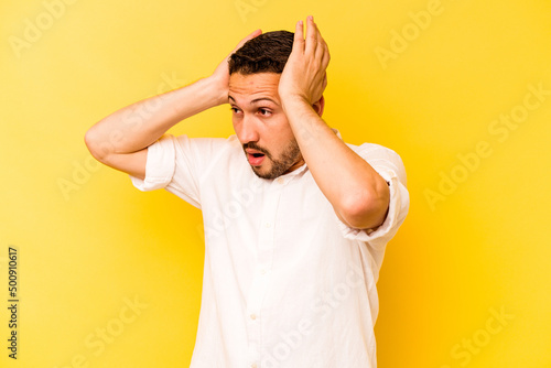 Young hispanic man isolated on yellow background screaming, very excited, passionate, satisfied with something. © Asier