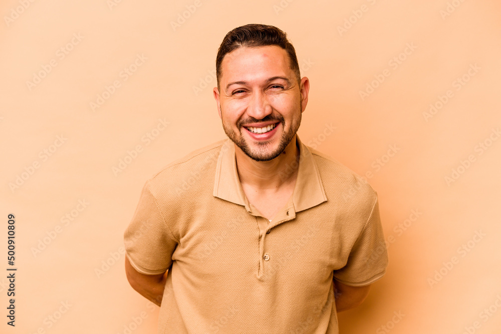 Young hispanic man isolated on beige background happy, smiling and cheerful. Young hispanic man isolated on beige background happy, smiling and cheerful.